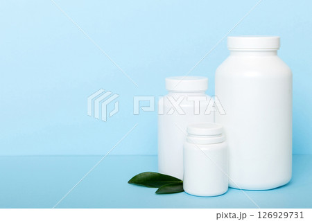 supplement pills with medicine bottle health care and medical top view. Vitamin tablets. Top view mockup bottle for pills and vitamins with green leaves, natural organic bio supplement, copy space 126929731