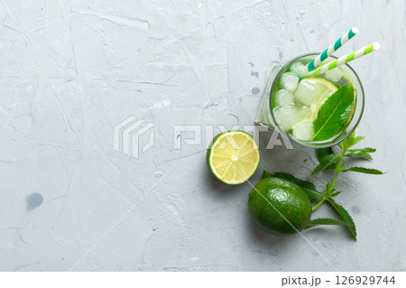 Caipirinha, Mojito cocktail, vodka or soda drink with lime, mint and straw on table background. Refreshing beverage with mint and lime in glass top view flat lay Caipirinha, Mojito cocktail, vodka or soda drink with lime, mint and straw on table background. Refreshing beverage with mint and lime in glass top view flat lay 126929744