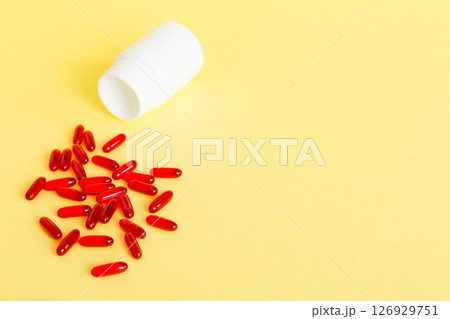 Red pills spilled around a pill bottle. Medicines and prescription pills flat lay background. Red medical capsules 126929751