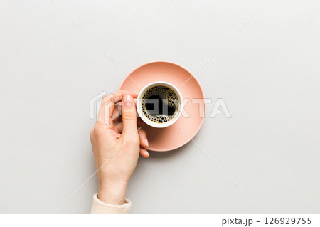 Minimalistic style woman hand holding a cup of coffee on Colored background. Flat lay, top view cappuccino cup. Empty place for text, copy space. Coffee addiction. Top view, flat lay Minimalistic style woman hand holding a cup of coffee on Colored background. Flat lay, top view cappuccino cup. Empty place for text, copy space. Coffee addiction. Top view, flat lay 126929755