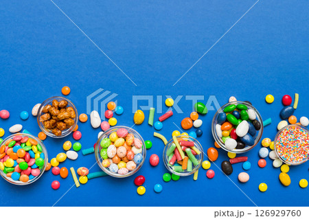 different colored round candy in bowl and jars. Top view of large variety sweets and candies with copy space different colored round candy in bowl and jars. Top view of large variety sweets and candies with copy space 126929760