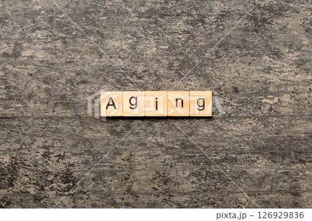 Aging word written on wood block. Aging text on cement table for your desing, concept Aging word written on wood block. Aging text on cement table for your desing, concept 126929836