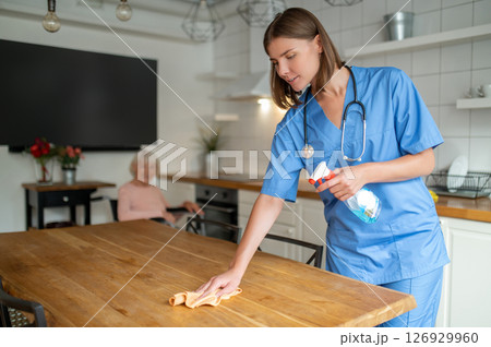 Young nurse cleaning the kitchen in the elderly woman house 126929960