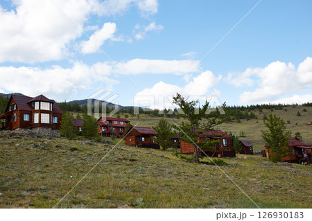 A tourist center with wooden houses in a rustic style against the backdrop of hills and trees. 126930183