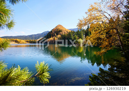 Beautiful autumn landscape. Orthodox chapel on the shore of the Emerald Lake. 126930219