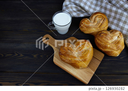 Homemade cakes and a cup of milk on a wooden board on a dark background Homemade cakes and a cup of milk on a wooden board on a dark background 126930282