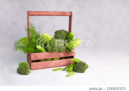 Green vegetables in a wooden box on a gray background. 126930323
