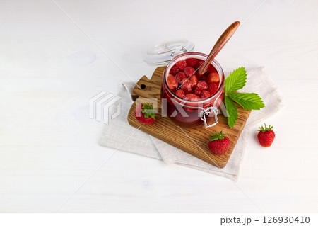 Strawberry jam in a glass jar and fresh berries. 126930410