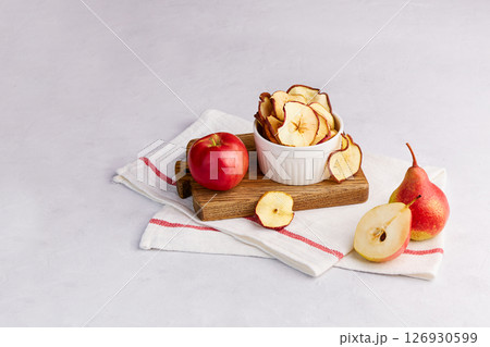 Homemade dried sliced apple and pear in a bowl on a light gray background. 126930599