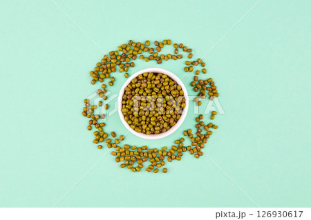 Mung beans in ceramic bowl on a green background. 126930617