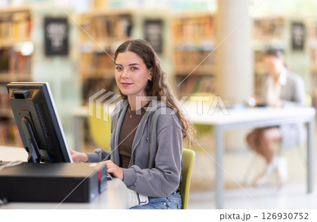Young female student working on computer in library Young female student working on computer in library 126930752
