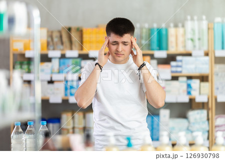 Young man visits pharmacy and suffers from headache Young man visits pharmacy and suffers from headache 126930798