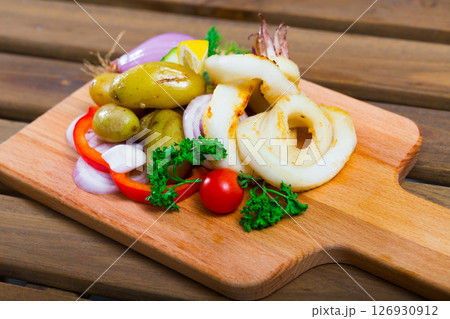 Squid rings with potatoes and fresh vegetables and herbs served at plate 126930912