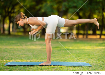 Young woman practicing yoga on green glade in summer park Young woman practicing yoga on green glade in summer park 126930968