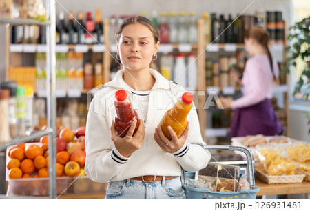 woman chooses juices against the background of buyers 126931481