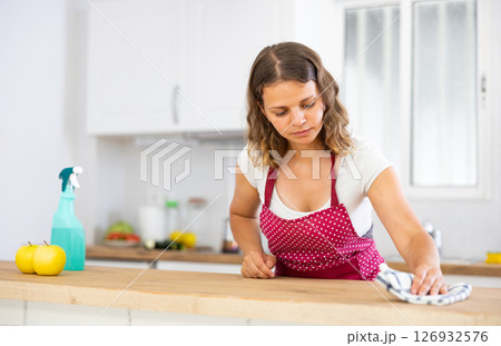 Focused young girl housewife cleaning table 126932576