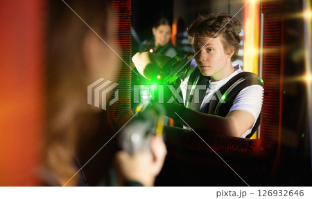 Portrait of positive man with laser gun having fun with her friends on lasertag arena 126932646