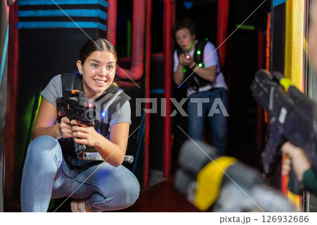 Smiling girl with laser pistol during playing laser tag with her friends in room 126932686