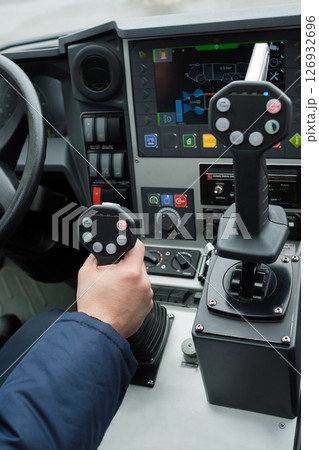 Close-up view of a driver operating heavy machinery with precision controls while on duty in an urban setting during daylight hours 126932696