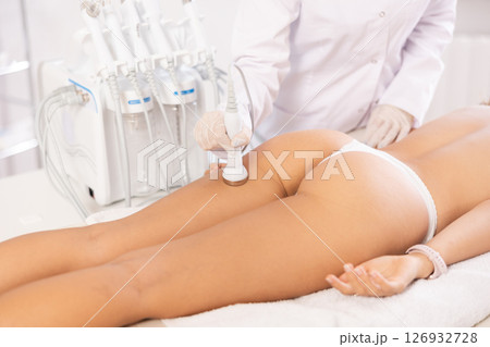 Aesthetician administering high frequency ultrasound procedure on buttocks of female patient Aesthetician administering high frequency ultrasound procedure on buttocks of female patient 126932728