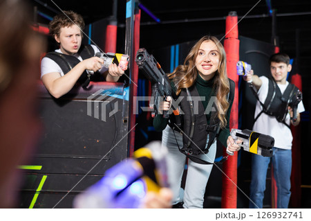 Two guys and one girl running and dodging while playing lasertag Two guys and one girl running and dodging while playing lasertag 126932741