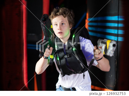 Boy running and dodging while playing lasertag Boy running and dodging while playing lasertag 126932753