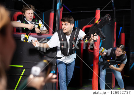 Portrait of excited people playing enthusiastically laser tag game two teams opposite each other in room 126932757