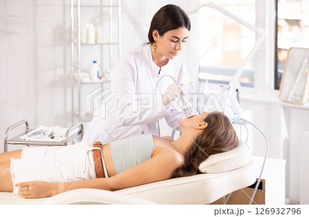 female doctor making facial beauty procedure with ice hummer female doctor making facial beauty procedure with ice hummer 126932796