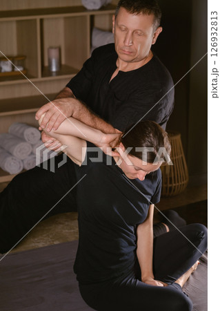 A man gives a Thai neck massage to a girl at a spa. A professional therapist performs a therapeutic neck massage on a girl 126932813