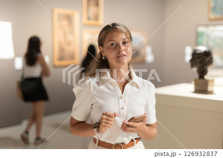 Girl with phone in hands walks around museum hall, view exhibition items 126932837