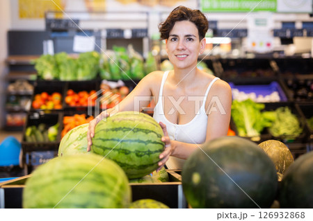 Female shopper holding watermelon in supermarket grocery section Female shopper holding watermelon in supermarket grocery section 126932868