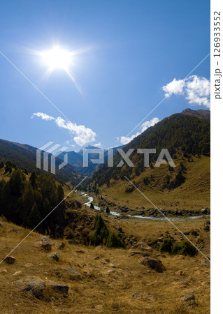 Sunlit Gorgeous Mountain Valley with Winding River and Forests in Kyrgyzstan Sunlit Gorgeous Mountain Valley with Winding River and Forests in Kyrgyzstan 126933552