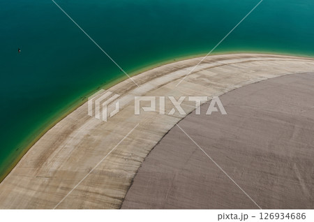 Aerial View of a Curved Shoreline and Calm Vibrant Green Waters 126934686