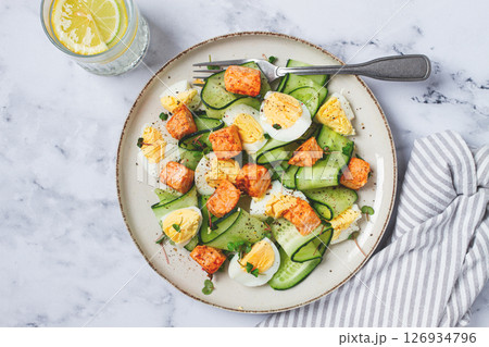 Delicious salmon and egg salad served on a plate with fresh cucumber and herbs for a healthy meal at lunchtime Delicious salmon and egg salad served on a plate with fresh cucumber and herbs for a healthy meal at lunchtime 126934796
