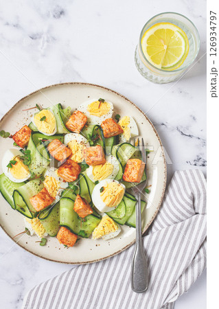 Delicious salmon and egg salad served on a plate with fresh cucumber and herbs for a healthy meal at lunchtime 126934797