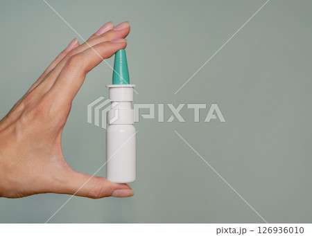 A nasal spray in a woman's hand close up. Background banner with copy space for text A nasal spray in a woman's hand close up. Background banner with copy space for text 126936010