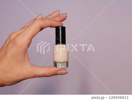 Nude beige nail polish in a woman's hand close up. Background banner with copy space for text Nude beige nail polish in a woman's hand close up. Background banner with copy space for text 126936011