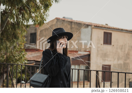 Elegant Woman In Total Black Walking With The Phone In The Town Park Elegant Woman In Total Black Walking With The Phone In The Town Park 126938021