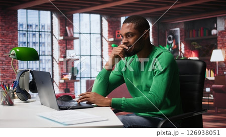 Black man doing remote work feeling uneasy and anxious at desk, shaking his legs and being jittery due to task completion and deadline. Freelancer working under pressure, anxiety. Camera B. Black man doing remote work feeling uneasy and anxious at desk, shaking his legs and being jittery due to task completion and deadline. Freelancer working under pressure, anxiety. Camera B. 126938051