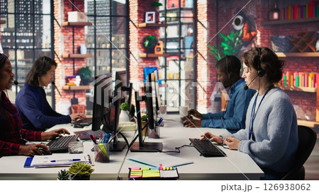 Call center agent helping customers regain access to accounts, resetting passwords. Employee in customer center workspace assisting clients needing help, providing helpful solutions, camera B 126938062