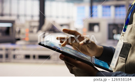 Close up of engineer using tablet to design solar panels factory layouts, utilizing CAD software and simulation tools, optimizing production systems in automated photovoltaics plant, camera A 126938184