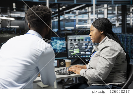 Data center engineering team using artificial intelligence neural networks technology. Professional and coworker in server room using AI programming language to configure specialized hardware 126938217