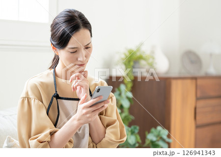 スマホを見ながら悩む女性 スマホを見ながら悩む女性 126941343