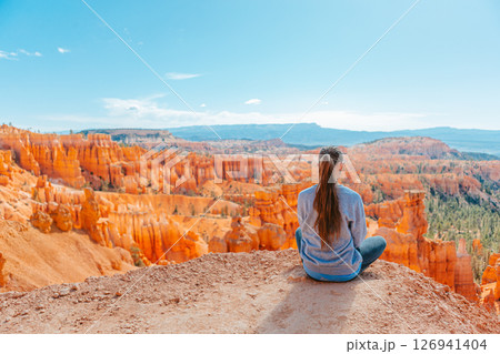 Hiker girl in Bryce Canyon hiking relaxing looking at amazing view during hike on summer travel in Bryce Canyon National Park, Utah, United States. Hiker girl in Bryce Canyon hiking relaxing looking at amazing view during hike on summer travel in Bryce Canyon National Park, Utah, United States. 126941404
