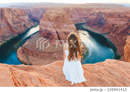 Happy girl on the edge of the cliff at Horseshoe Band Canyon in Page, Arizona. Adventure and tourism concept. Beautiful nature in USA Happy girl on the edge of the cliff at Horseshoe Band Canyon in Page, Arizona. Adventure and tourism concept. Beautiful nature in USA 126941412
