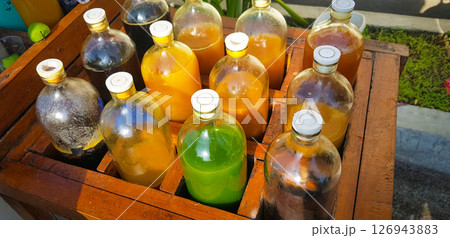 Colorful Bottles of traditional natural organic medicine locally called jamu, Displayed in Wooden Case on a Sunny Day 126943883