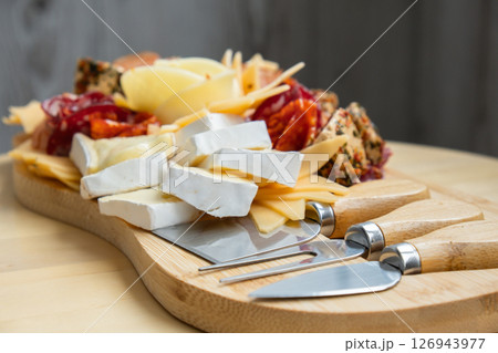 Cheese and meat charcuterie board. Gift present idea, dinner lunch plate. Minimal effort visually pleasing snacks. Simple meal preparation with special cheese knives Cheese and meat charcuterie board. Gift present idea, dinner lunch plate. Minimal effort visually pleasing snacks. Simple meal preparation with special cheese knives 126943977