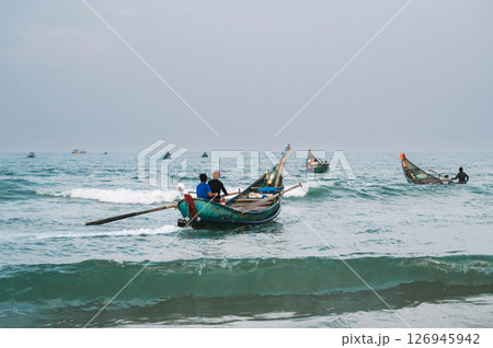 Vietnamese fishermen men on wooden traditional boats in the sea at fishing village in Vietnam Vietnamese fishermen men on wooden traditional boats in the sea at fishing village in Vietnam 126945942