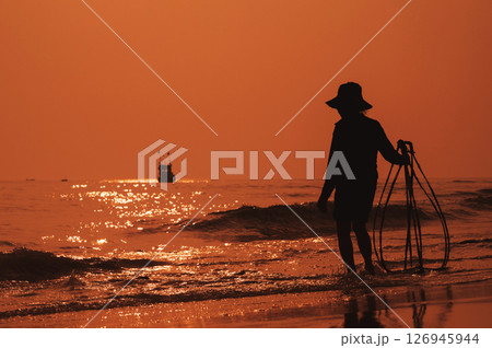 Silhouette of Vietnamese woman on the shore of sea with ship in a fishing village in the morning at sunrise in Vietnam 126945944