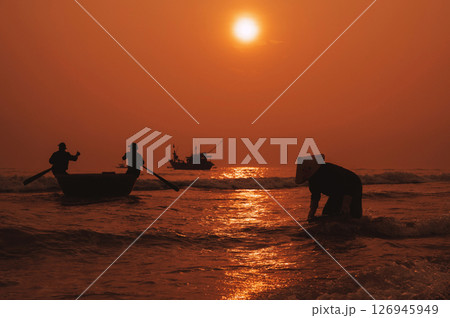 Silhouettes of Vietnamese fishermen in a round basket boat and a woman in a straw hat in a fishing village in the morning at sunrise in Vietnam 126945949